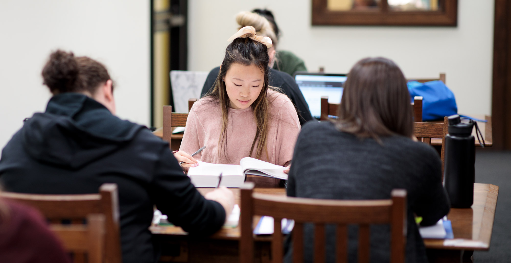 Student studies with peers in the library.